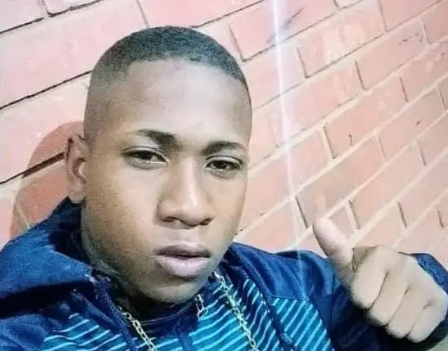 Homem jovem, negro, posa para foto com expressão séria diante de parede de tijolos, em imagem usada para ilustrar debate sobre violência policial e racismo estrutural